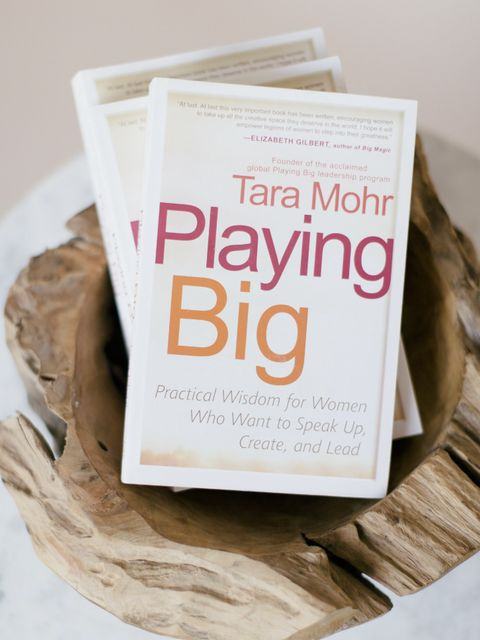 Copies of Playing Big by Tara Mohr in a driftwood bowl