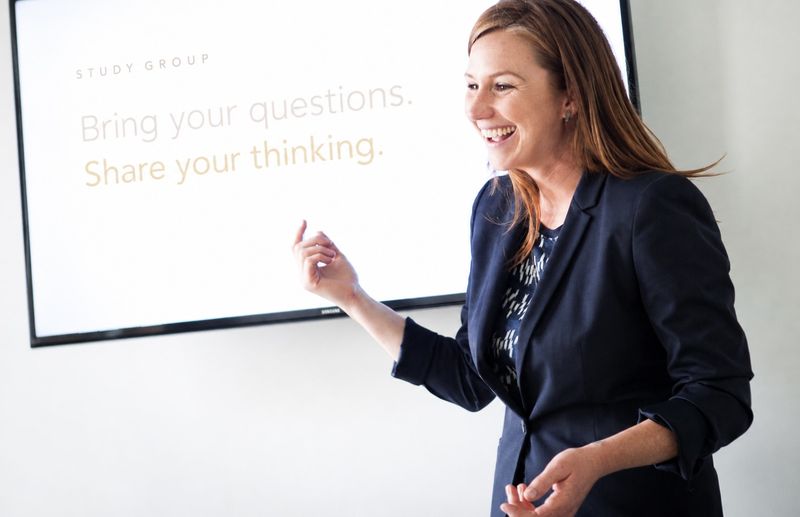 Sonya smiling and gesturing beside a screen that reads Study Group: Bring your questions. Share your thinking.
